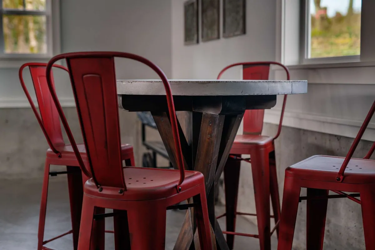 A friendly, welcoming dining area with red metal chairs and a sturdy wooden table set near a window, suggesting a lively spot for sharing meals or gathering before heading out to explore. The natural light and visible view outside reinforce the idea of the home as a launch pad for local adventures.